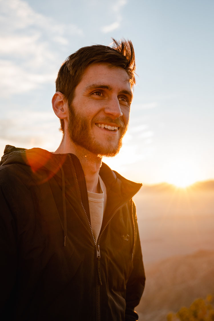 Man smiles as the sun sets over Joshua Tree National Park